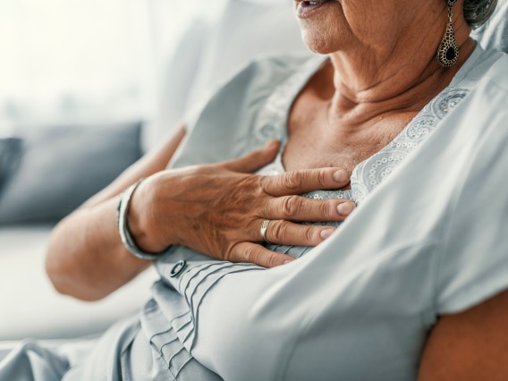 elderly hispanic woman sitting with her hand over her heart