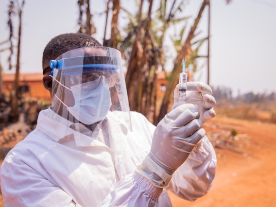 doctor checks syringe outside on dirt road