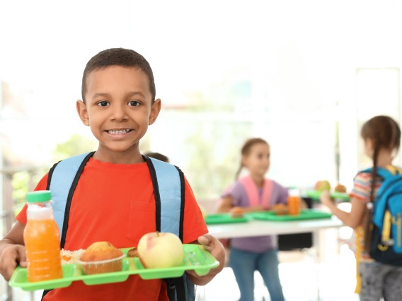 children holding lunch trays at school