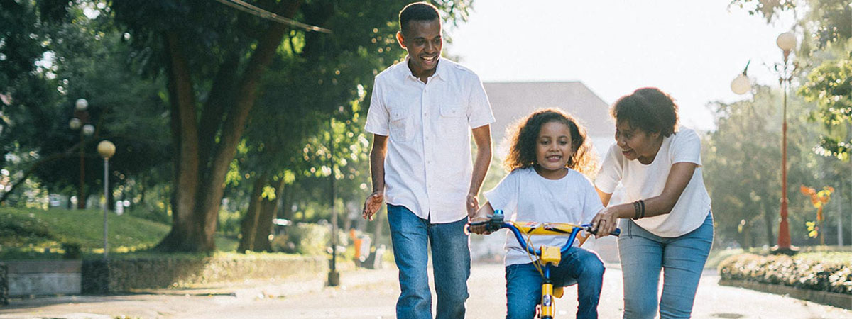 Parents helping daughter learn to ride bicycle