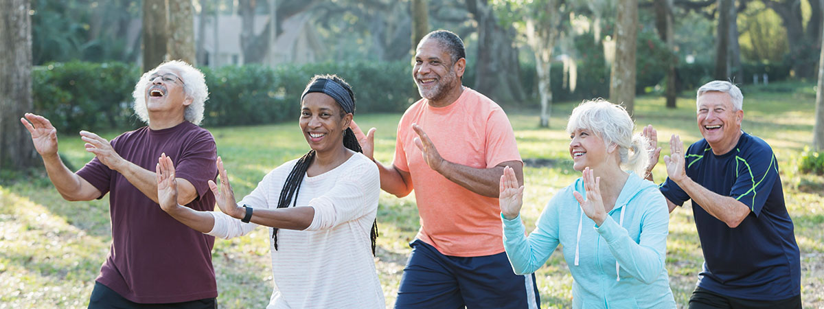  A group of five multi-ethnic seniors doing Tai Chi in the park.